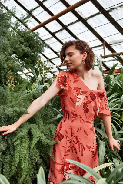 Beautiful model girl In botanical garden. Fashion style with makeup and red dress - Foto, afbeelding