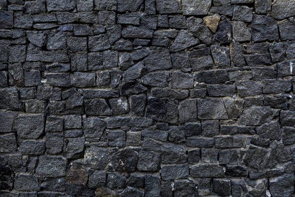 Steinzaun. Zaun aus schwarzen Steinen von unregelmäßiger Form. einen Zaun aus abgebrochenen Steinen. Steinbeschaffenheit. - Foto, Bild