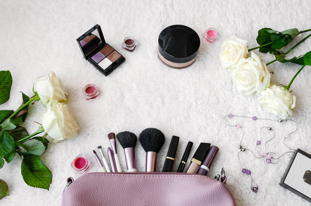 top view of the working area notebook with pen and decorative cosmetics for makeup, soft brushes and flowers, beautiful background closeup - Photo, Image