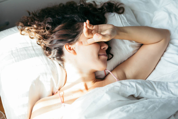 woman sleeping in bed bright light on face morning time - Photo, Image
