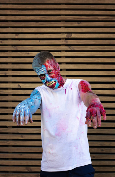 young guy in makeup. zombie. lacerated wounds. on wooden background. Halloween concept - Photo, Image