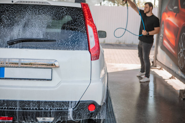 strong man washing car at self carwash outdoors summer time - Foto, immagini