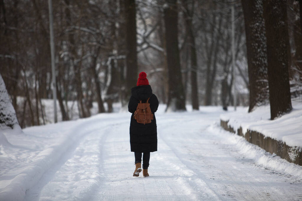 женщина в зимнем наряде прогулка по снежной дороге парка красная шляпа
 - Фото, изображение