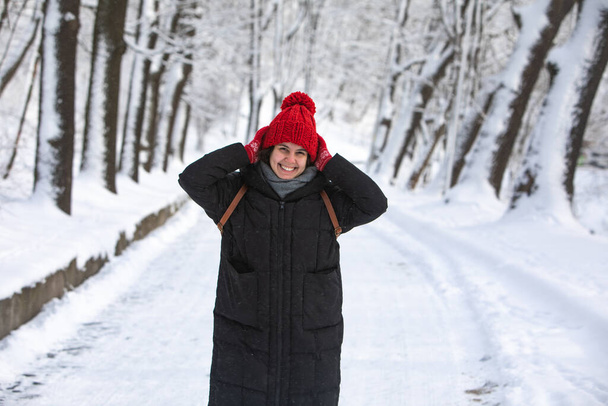 giovane bella donna sorridente in cappotto invernale con cappello rosso al parco forestale della città nevicato tempo
 - Foto, immagini