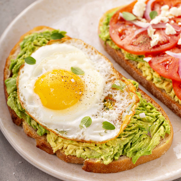 Avocado toasts with fried egg and heirloom tomatoes - Фото, изображение