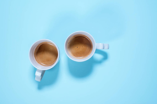 Frais deux tasses cappuccino café avec du lait sur la couleur bleu pastel. Contexte alimentaire. Vue de dessus. Pose plate. Minimalisme
 - Photo, image
