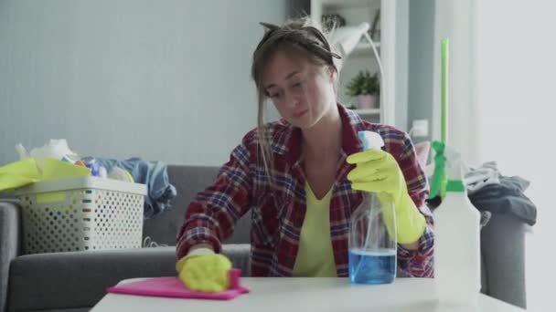 Müde Frau versucht mit einem rosa Schwamm, den Staub vom Tisch zu entfernen - Filmmaterial, Video