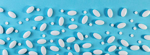 Medical background. White Pills pattern on blue background. Flat lay. pharmaceuticals antibiotics pills medicine. Medicine concept. long wide banner - Photo, image
