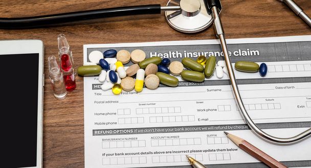 personal health insurance claim form with pills, syringe, mobile phone, stethoscope - Photo, Image