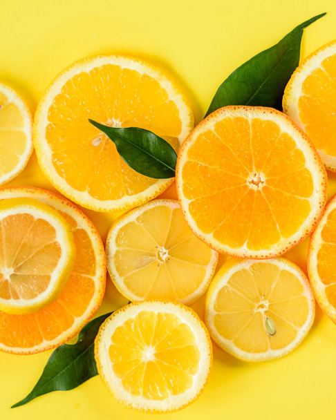 Close up top view of sliced oranges and lemons on a yellow background - Fotó, kép
