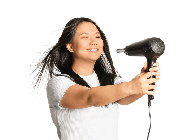 Hermosa mujer asiática con secador de pelo sobre fondo blanco
 - Foto, Imagen