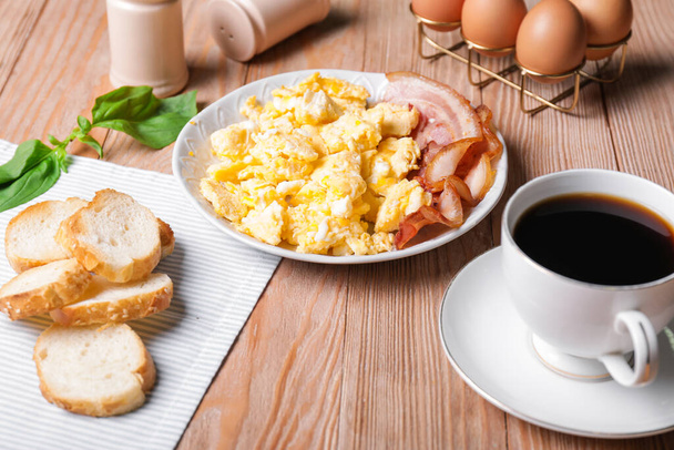 Plate with scrambled egg and bacon on table - Photo, Image