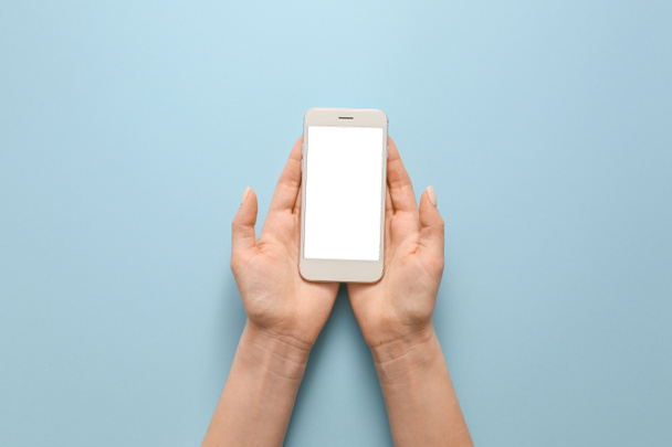 Γυναικεία χέρια με κινητό τηλέφωνο στο φόντο χρώμα - Φωτογραφία, εικόνα