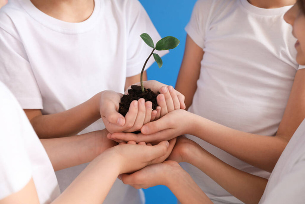 Crianças pequenas com planta e solo no fundo de cor. Celebração do Dia da Terra
 - Foto, Imagem