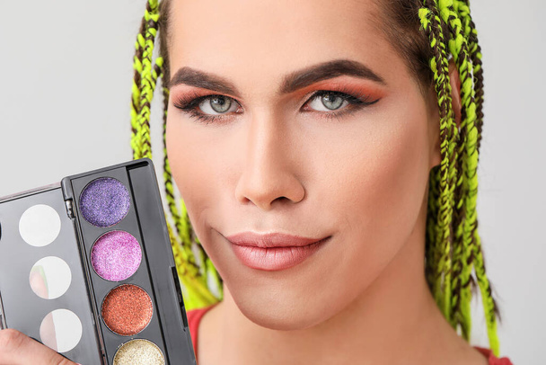 Transgender makeup artist with decorative cosmetics on light background - Photo, Image