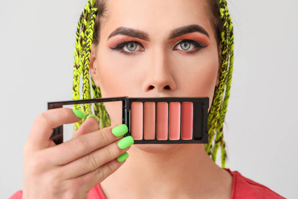 Artista de maquiagem transexual com cosméticos decorativos em fundo claro
 - Foto, Imagem