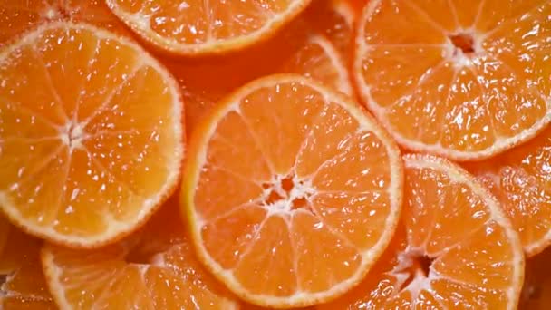 Fresh sliced orange fruit texture on rotating background. Top view. Citrus fruits. Vegan and raw food concept. Juicy oranges background - Filmati, video