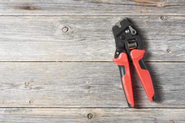 Tool for crimping stranded electrical wires. Crimping tool for electrician or Builder on a grey wooden background - Photo, Image