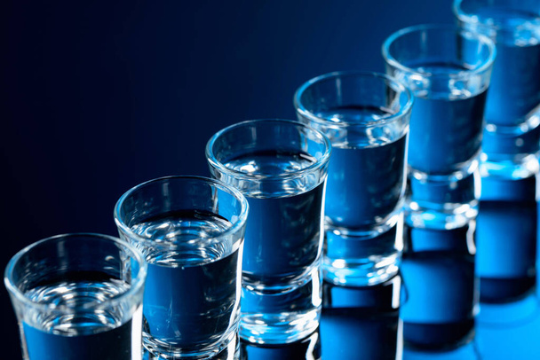Wodkagläser auf schwarzem, reflektierendem Hintergrund. Selektiver Fokus. - Foto, Bild