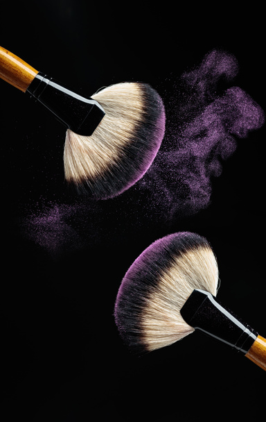 Concept de maquillage avec des pinceaux de maquillage professionnels avec fard à paupières violet brillant isolé sur fond noir. Espace de copie
. - Photo, image