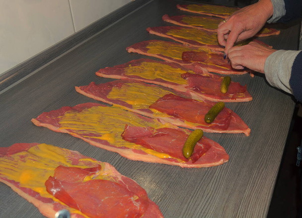 Préparation de roulades de bœuf frais, viande crue enrobée de moutarde et d'oignons. - Photo, image