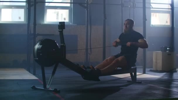 Slow motion: Rower trains, cardio athlete training. One man in an atmospheric fitness room in the sunlight in a rowing machine. - Video