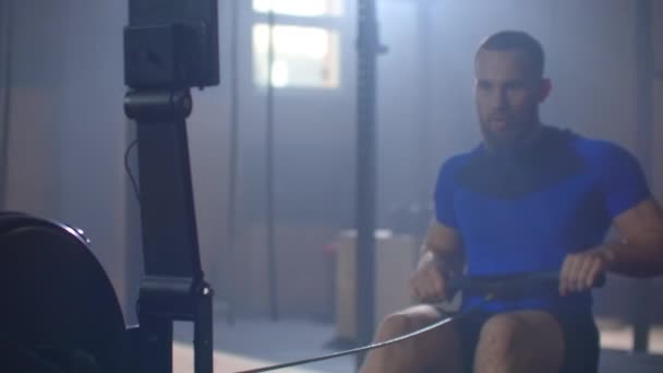 Movimiento lento: Un remador de hombres entrena en una sala de fitness en un remo
 - Imágenes, Vídeo