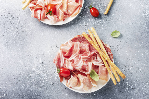 traditional italian antipasto with ham, salami and bread sticks, selective focus image - Foto, afbeelding
