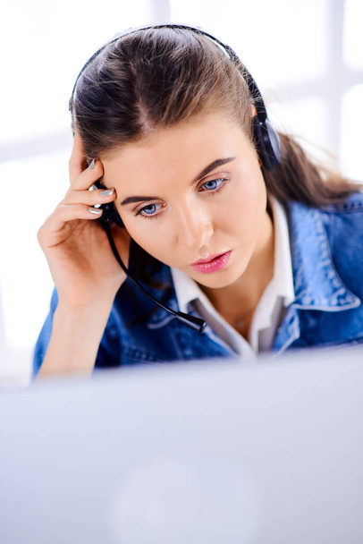 Nuori puhelinkeskus naisagentti selailee internetiä tietokoneellaan
 - Valokuva, kuva