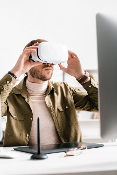 Selective focus of 3d artist using virtual reality headset near graphics tablet and computer on table in office - Photo, Image