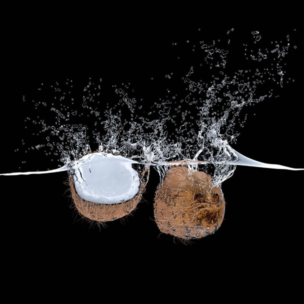 3d render kókuszdió gyümölcs esik a vízbe, és ami nagy fröccsenések. fekete háttér senki körül. a frissesség és az étrend fogalma, trópusi ételek. - Fotó, kép