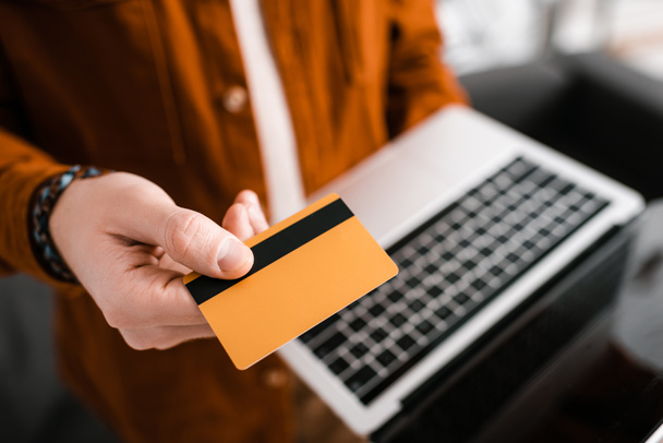 Selective focus of 3d artist holding credit card and laptop with blank screen  - Photo, Image