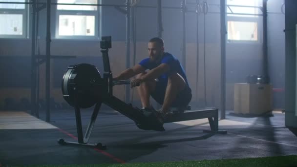 Slow motion: Rower trains, cardio athlete training. One man in an atmospheric fitness room in the sunlight in a rowing machine. - Video