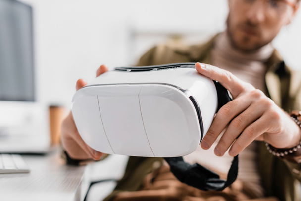 Focus sélectif de l'artiste 3d tenant casque de réalité virtuelle à table
  - Photo, image