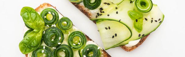 top view of fresh cucumber toasts with seeds and basil leaves isolated on white, panoramic shot - Φωτογραφία, εικόνα