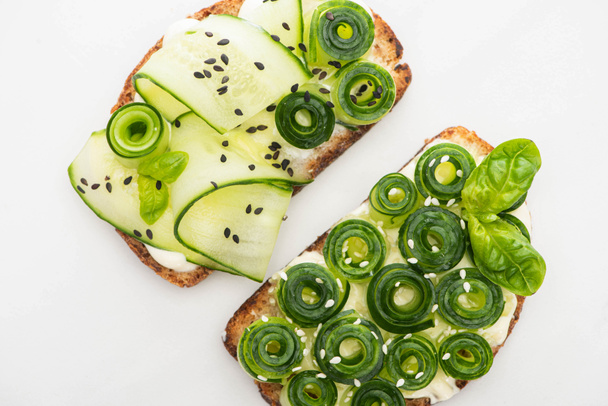 top view of fresh cucumber toasts with seeds and basil leaves isolated on white - Valokuva, kuva