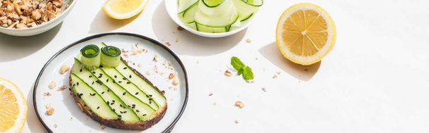 fresh cucumber toast with seeds near mint leaves and lemon on white background, panoramic shot - Foto, immagini