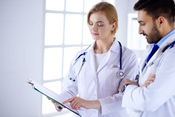 Twee gemengde rassen artsen met een map en praten over patiënt - Foto, afbeelding