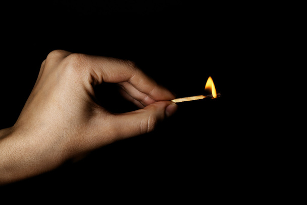 Burning match in hand on black background - Photo, Image