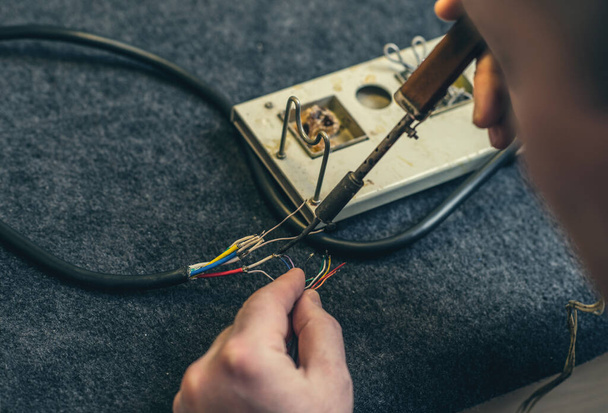 Close-up of person hands and soldering iron, tool and wires. Soldering process at home - Valokuva, kuva