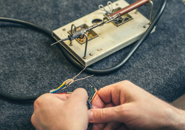 Close-up of person hands and soldering iron, tool and wires. Soldering process at home - Фото, зображення