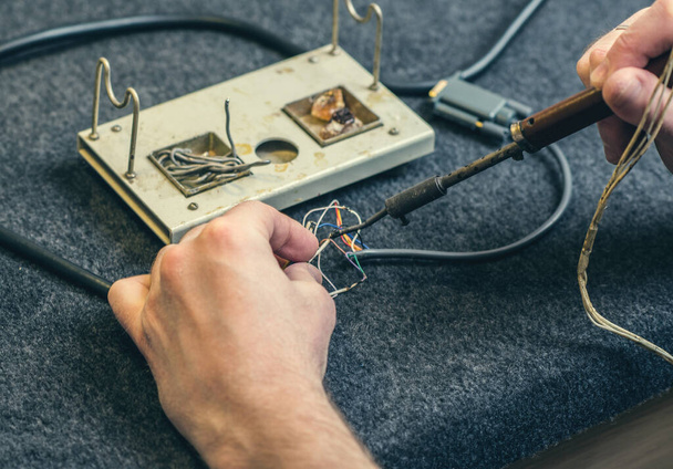 Close-up of person hands and soldering iron, tool and wires. Soldering process at home - Photo, image