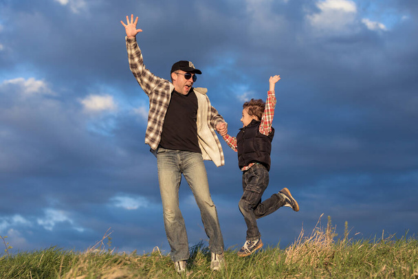 Pai e filho caminhando no campo durante o dia. Pessoas a divertir-se ao ar livre. Conceito de família amigável
. - Foto, Imagem