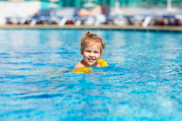 little girl is swimming in the pool in armbands. - Foto, Imagen