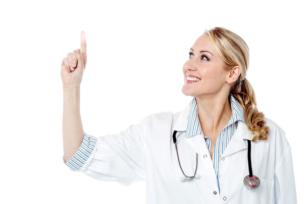 Smiling female doctor pointing upwards - Foto, imagen