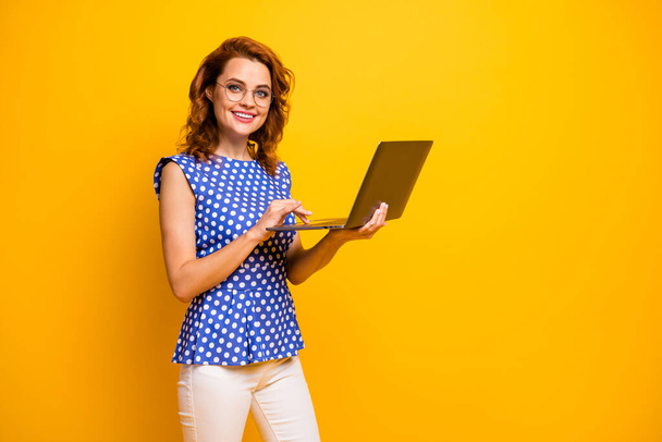 Profile photo of beautiful friendly lady hold notebook hands search information online for client customer wear specs polka-dot blue shirt white pants isolated yellow color background - Φωτογραφία, εικόνα