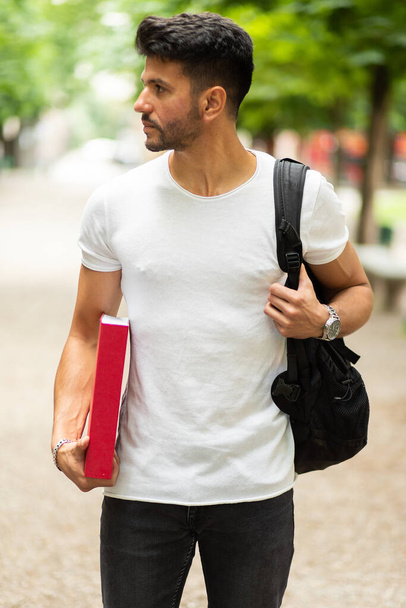Handsome male student with book in park - Photo, image