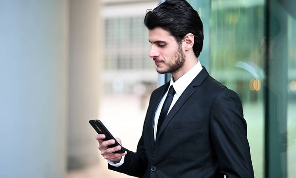 Handsome young manager using a smartphone outdoor - Foto, imagen