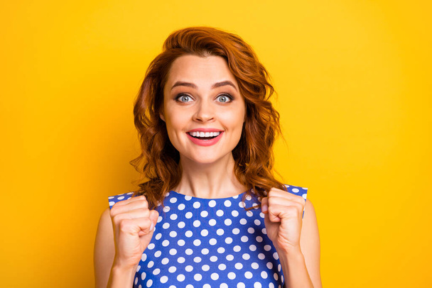 Closeup photo of pretty wavy ginger lady raising fists beaming smiling competition supporting sports team wear retro style polka-dot blue white shirt isolated yellow color background - Foto, immagini