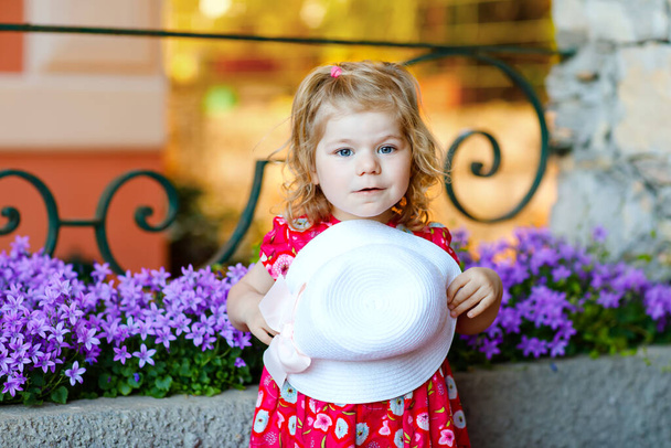 Porträt der schönen kleinen Gorgeus schöne Kleinkind Mädchen in rosa Sommer Look Kleidung, Modekleid, Kniestrümpfe und Hut. Glückliches gesundes Baby posiert vor buntem Haus. - Foto, Bild